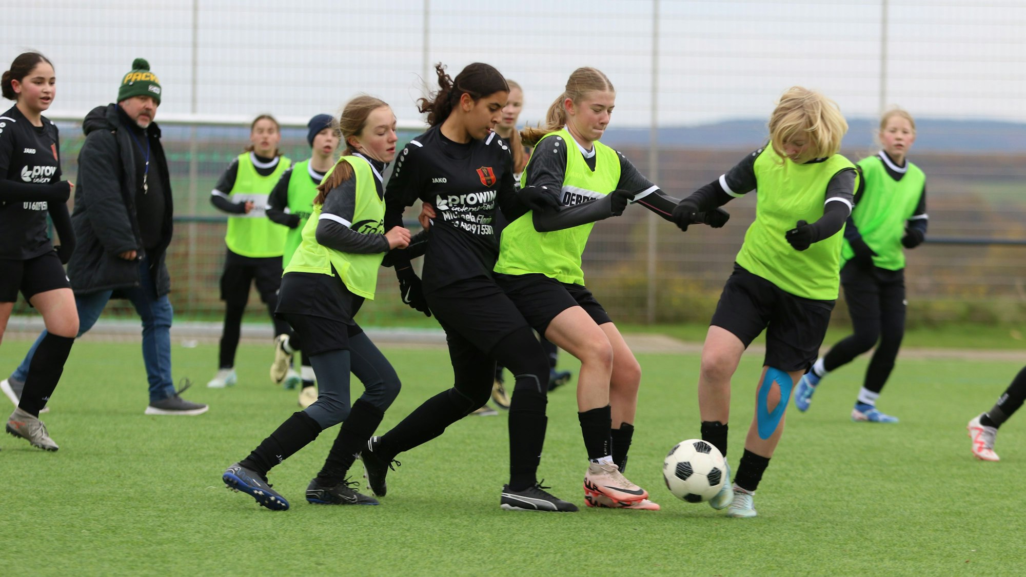 Fußballerinnen im Zweikampf. Da beide Mannschaften schwarze Trikots und Hosen trugen, mussten die Gastgeberinnen grellgrüne Leibchen überziehen.
