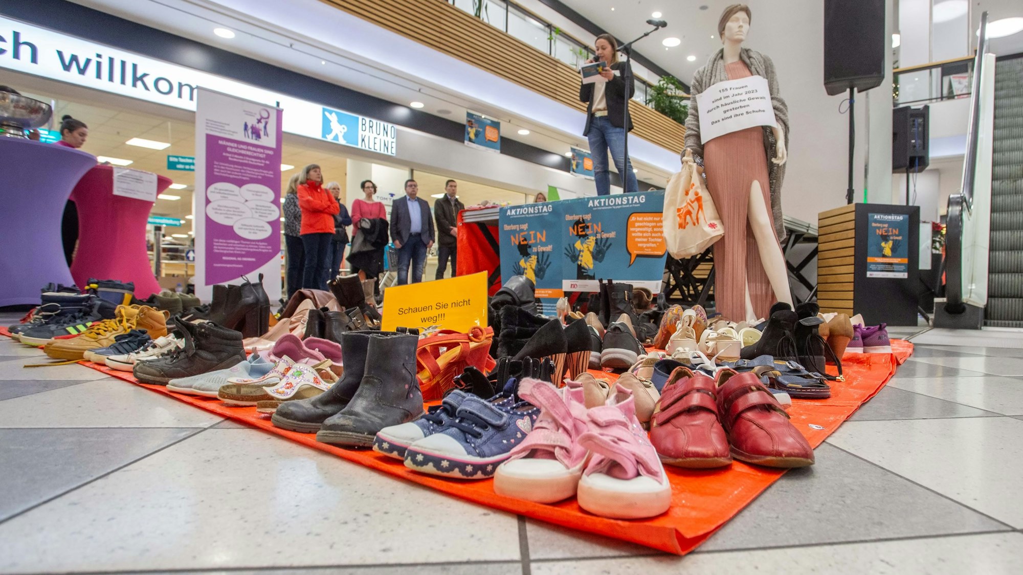 Auf dem Boden eines Einkaufszentrums sind zahlreiche Schuhe nebeneinander aufgestellt