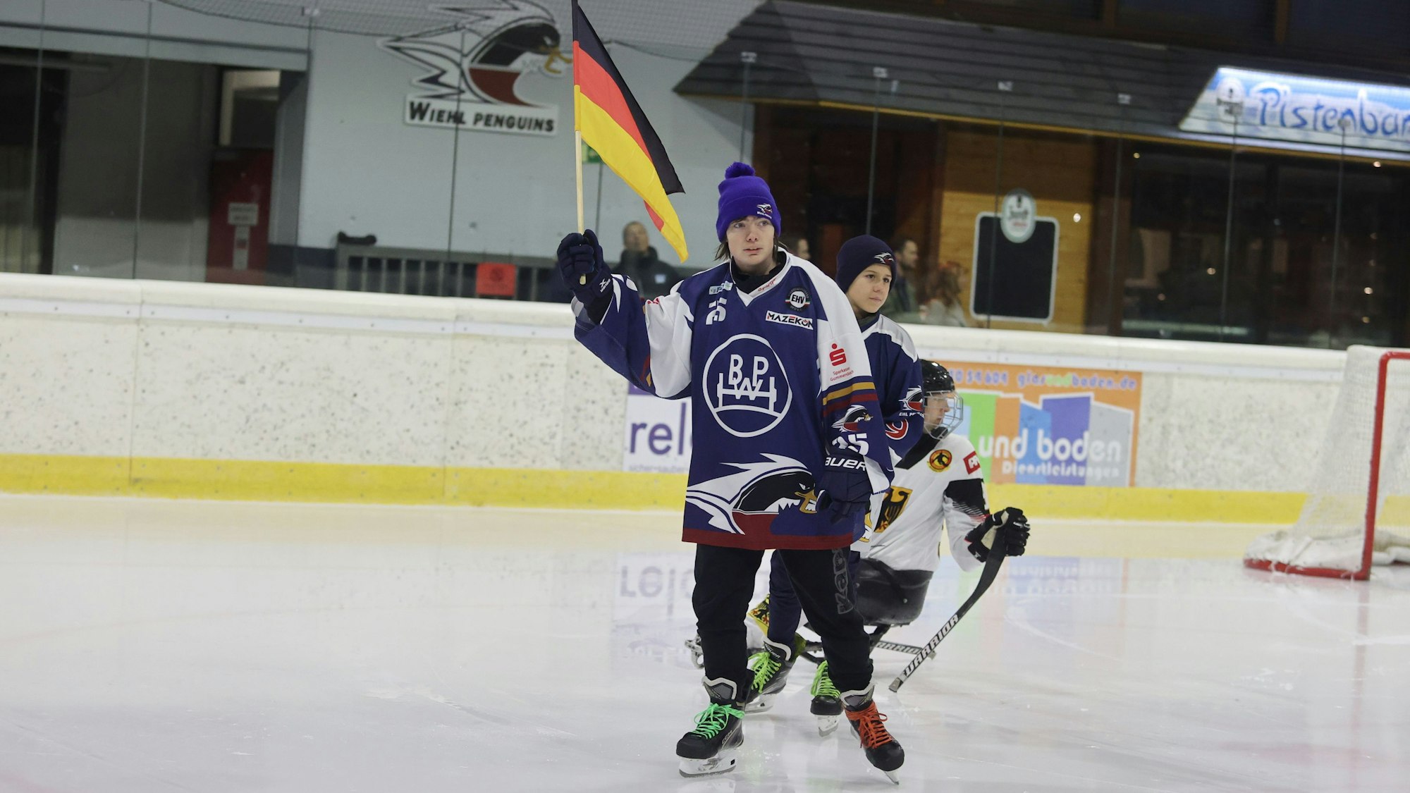 Ein Fahnenträger auf Schlittschuhen schwenkt die Deutschland-Fahne.