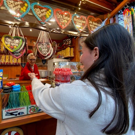 Zu sehen ist eine Frau, die gebrannte Mandeln kauft.