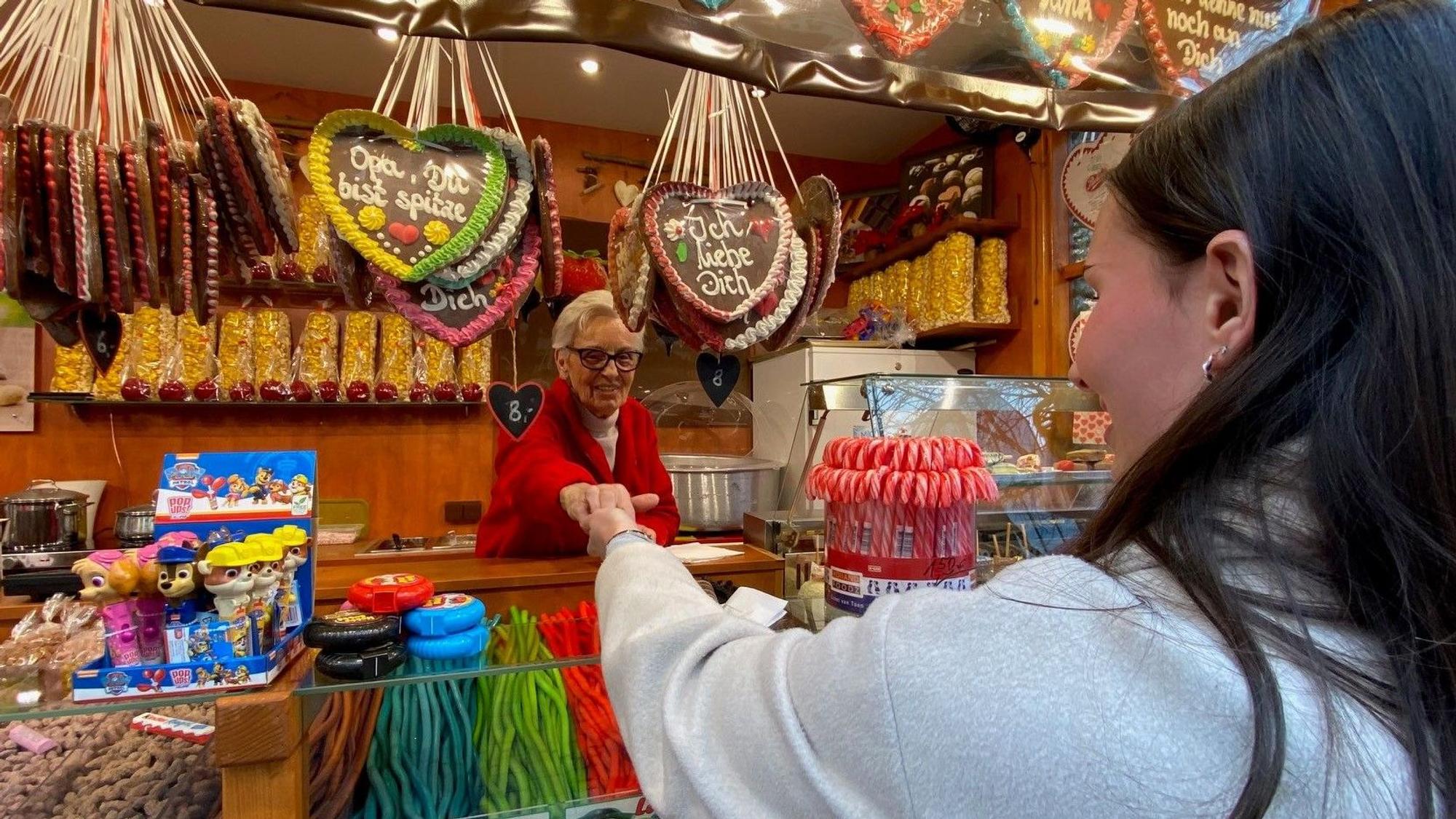 Zu sehen ist eine Frau, die gebrannte Mandeln kauft.