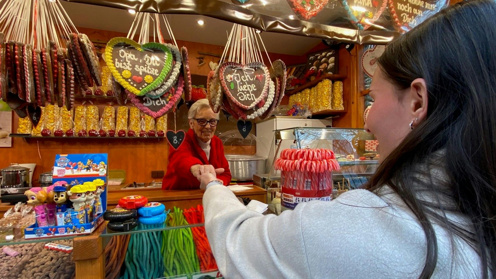 Zu sehen ist eine Frau, die gebrannte Mandeln kauft.