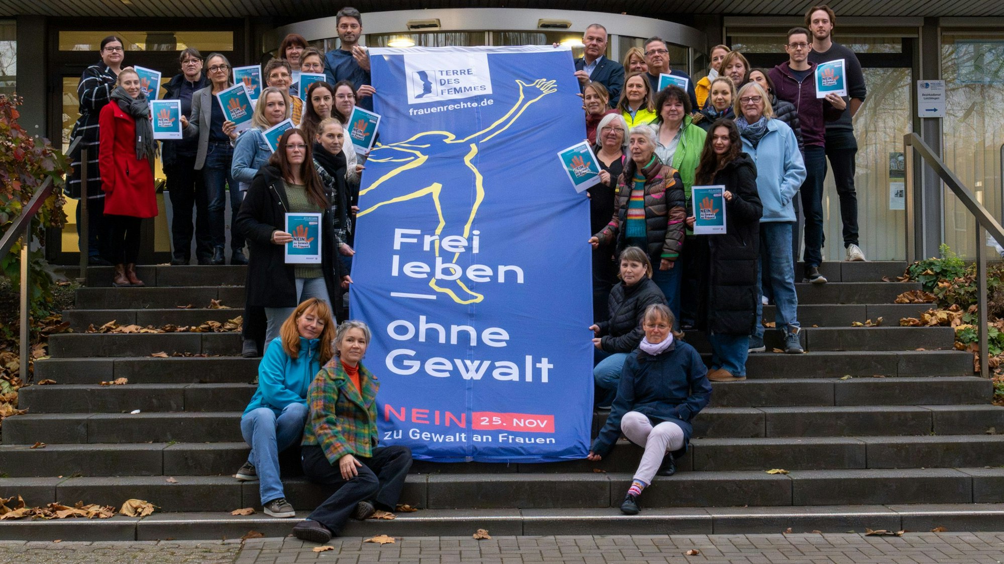 Zeigen Flagge: Bürgermeister Frank Steffes, die Gleichstellungsbeauftragte Nadja Kischka-Wellhäußer und Mitarbeiterinnen und Mitarbeiter der Stadtverwaltung mit der Aktionsflagge vor dem Leichlinger Rathaus.