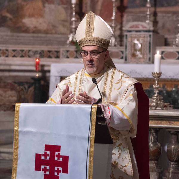 Zu sehen ist Pierbattista Pizzaballa in der Vorderansicht in einer Kirche vor einem Rednerpult in geistlicher Kleidung.