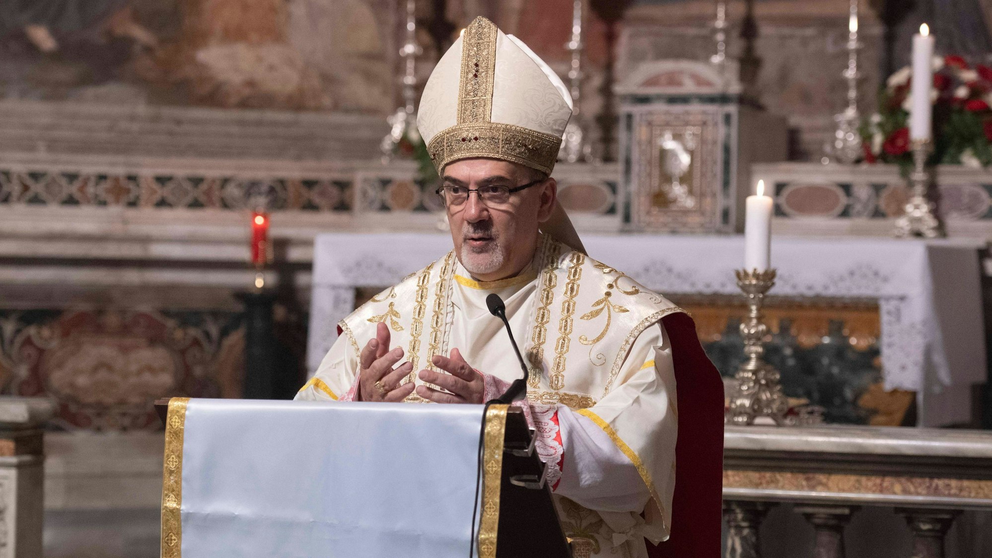 Zu sehen ist Pierbattista Pizzaballa in der Vorderansicht in einer Kirche vor einem Rednerpult in geistlicher Kleidung.