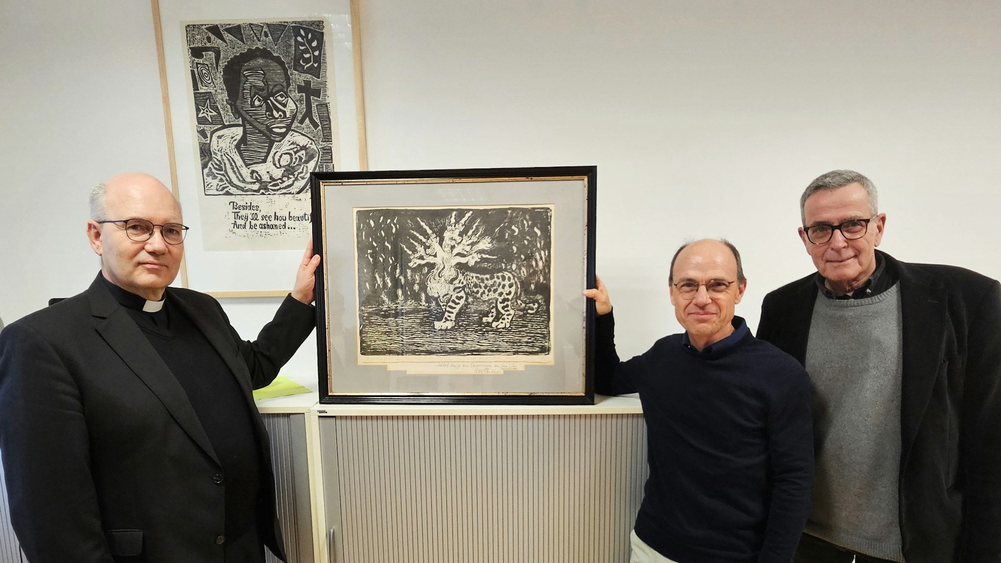 Auf dem Foto (v.l.) halten Bischof Helmut Dieser und Georg Toporowsky ein Bild von Otto Pankok. Christoph Leisten steht daneben..
