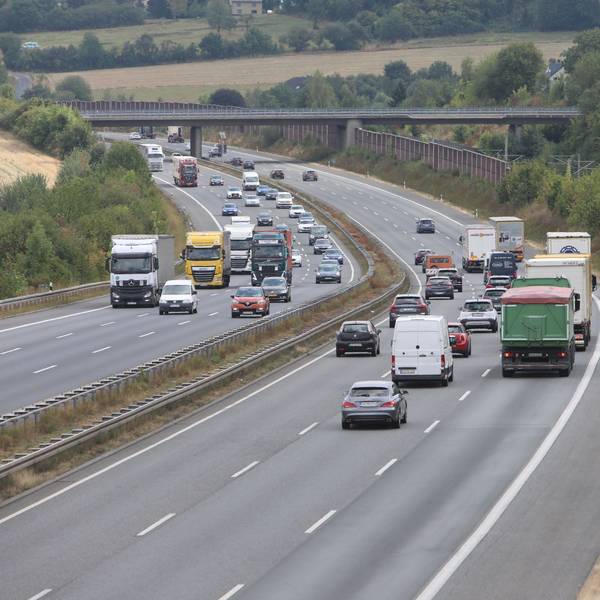 Mehrere Pkw und Lkw fahren auf der sechsspurigen Autobahn.