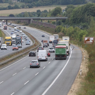 Mehrere Pkw und Lkw fahren auf der sechsspurigen Autobahn.