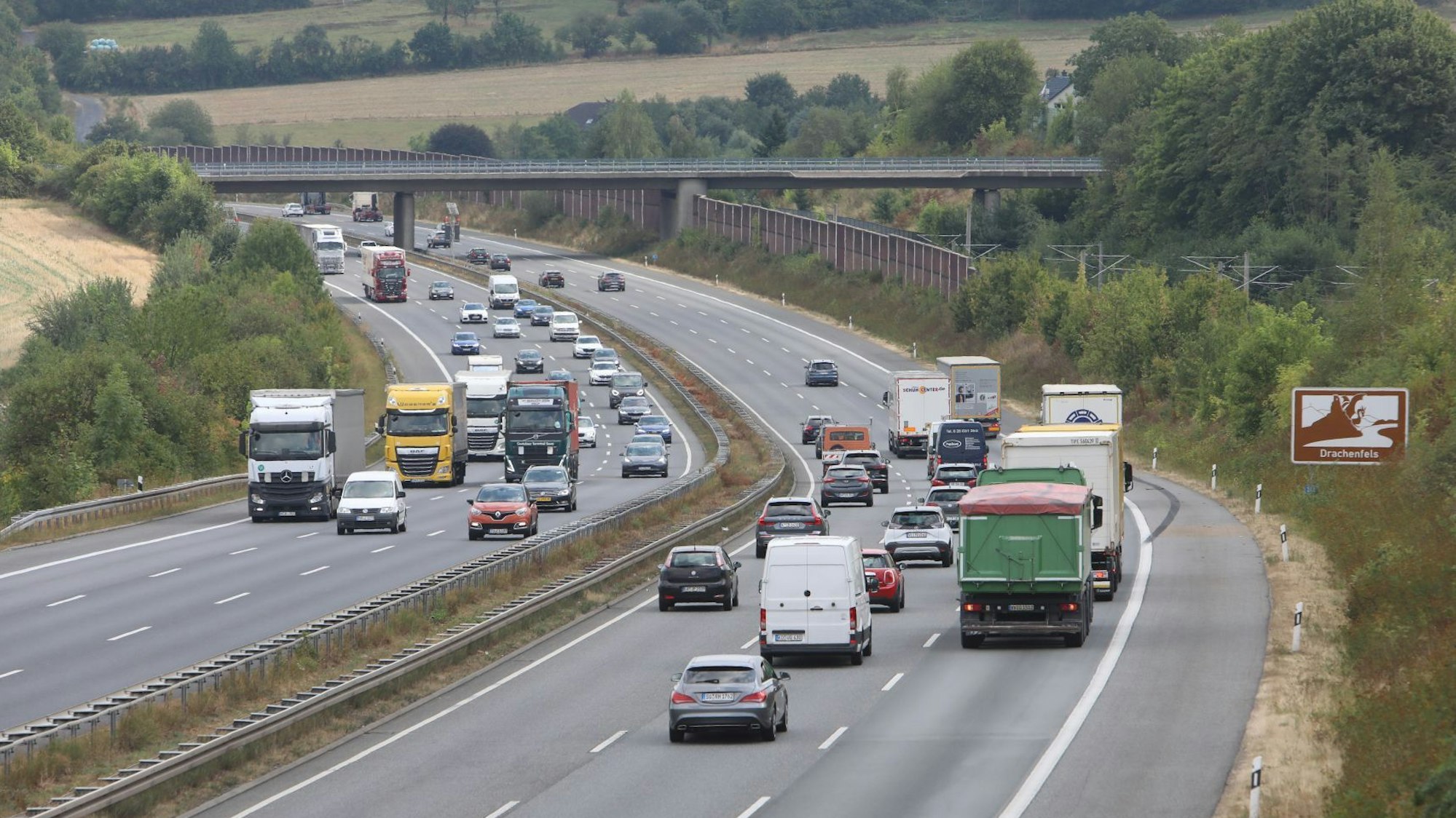 Mehrere Pkw und Lkw fahren auf der sechsspurigen Autobahn.