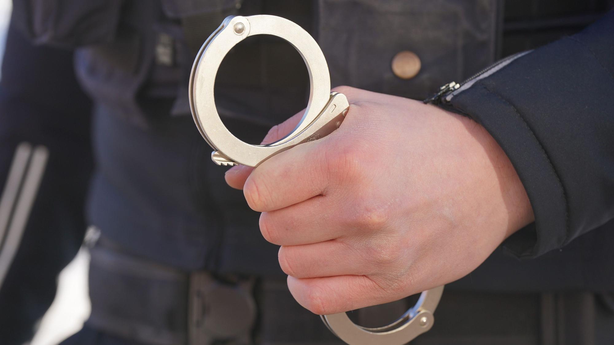 Ein Polizist hält Handschellen in der Hand.