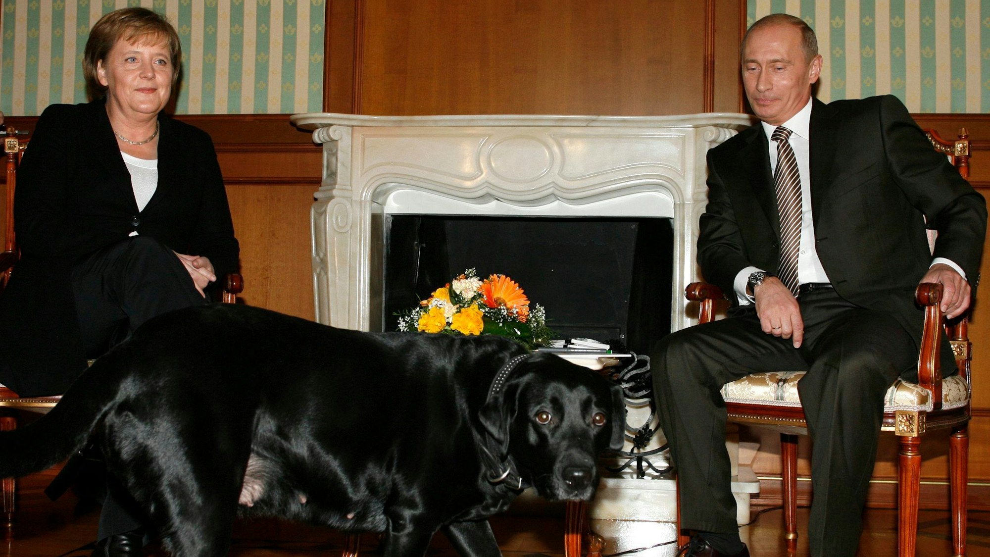 FILE - German Chancellor Angela Merkel and Russian President Vladimir Putin, look on as Putin's dog Cony walks past, during the meeting in Putin's residence in the Russian Black Sea resort of Sochi, Sunday, Jan. 21, 2007. (AP Photo/Mikhail Metzel, File)