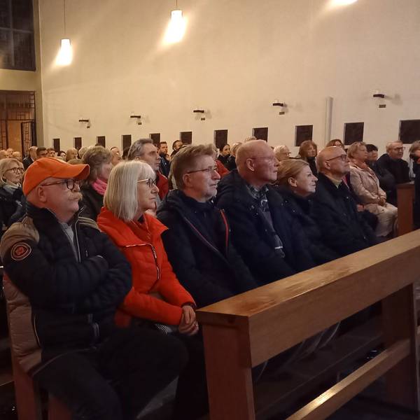 Ein Blick ins Pfarrzentrum, wo viele Menschen dicht gedrängt auf Bänken sitzen.