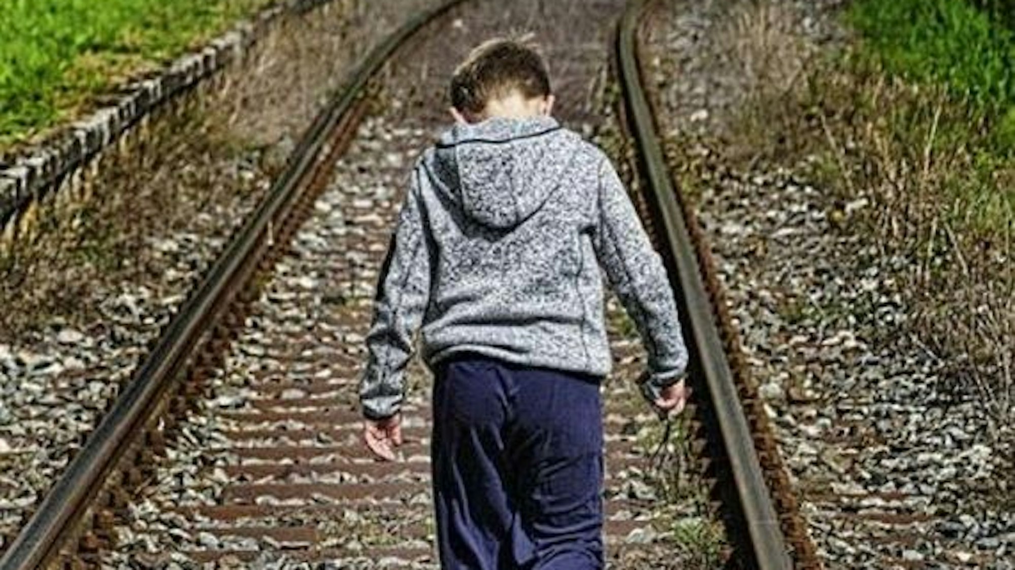 Ein Junge auf Bahngleisen
