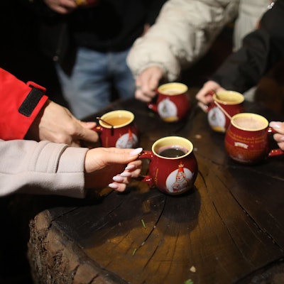 Besucher greifen zu mehreren Glühweintassen.