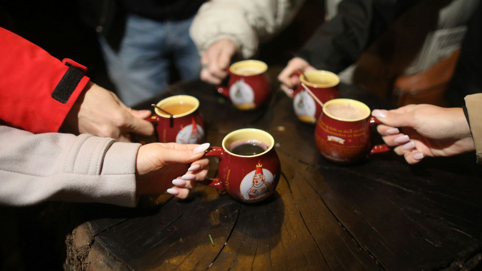 Besucher greifen zu mehreren Glühweintassen.