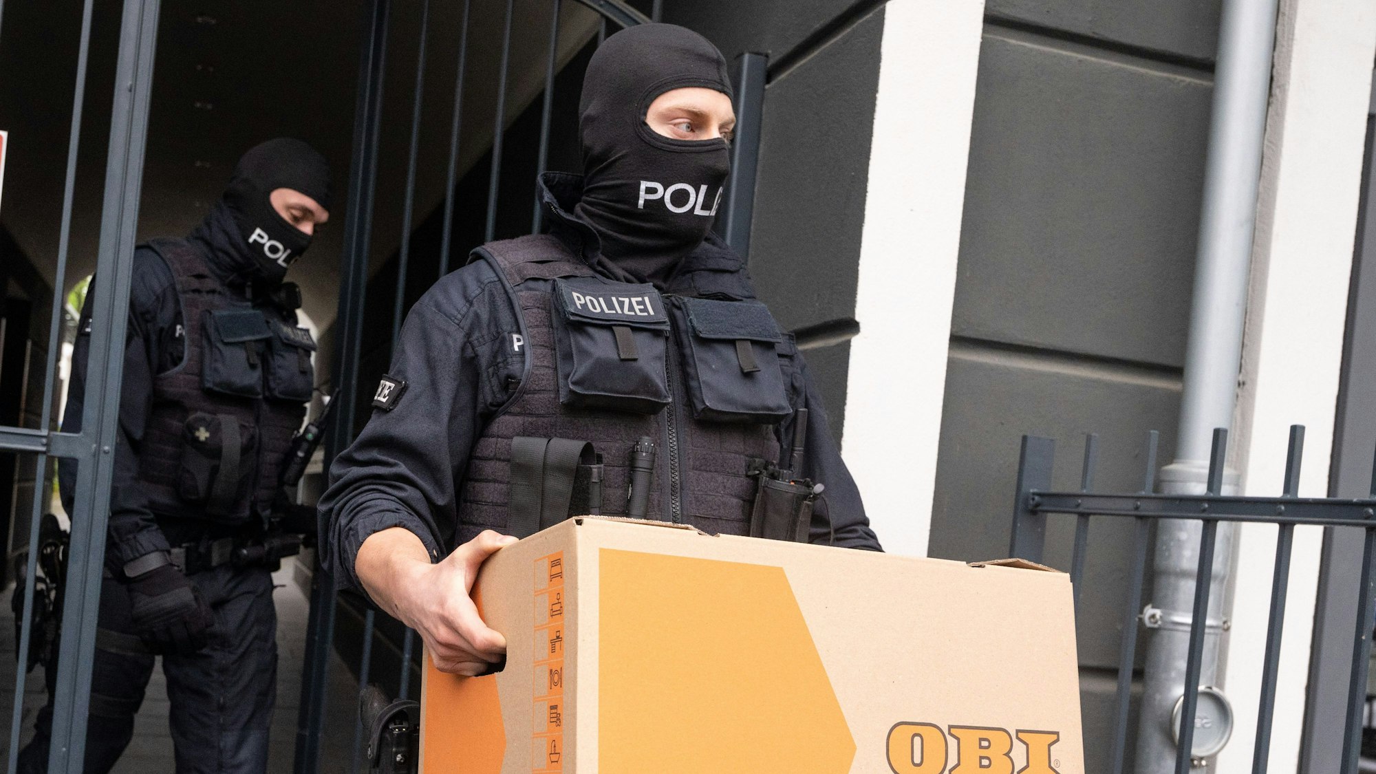 Ein Polizist trägt einen Karton aus einem Gebäude.