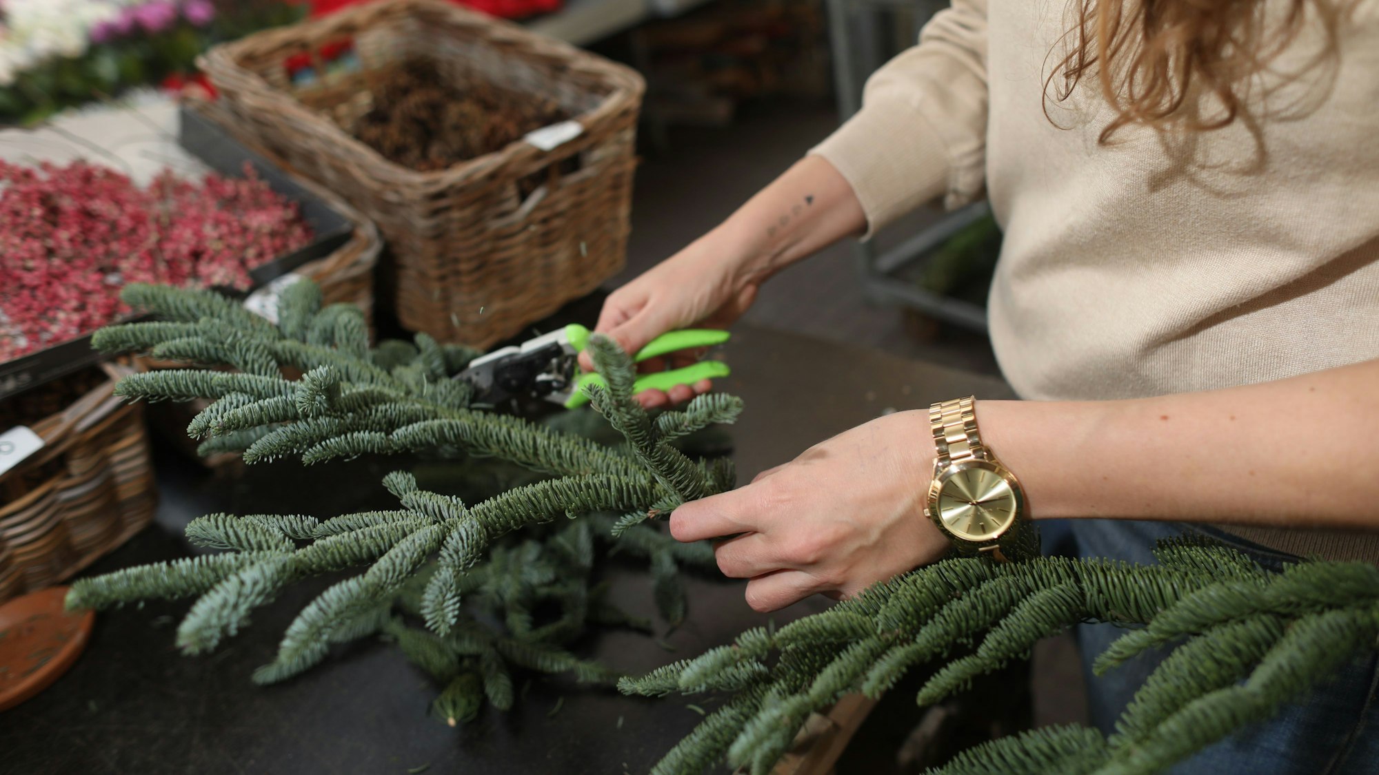 Das Tannengrün muss in die passende Größe geschnitten werden, damit man es um den Kranz wickeln kann.