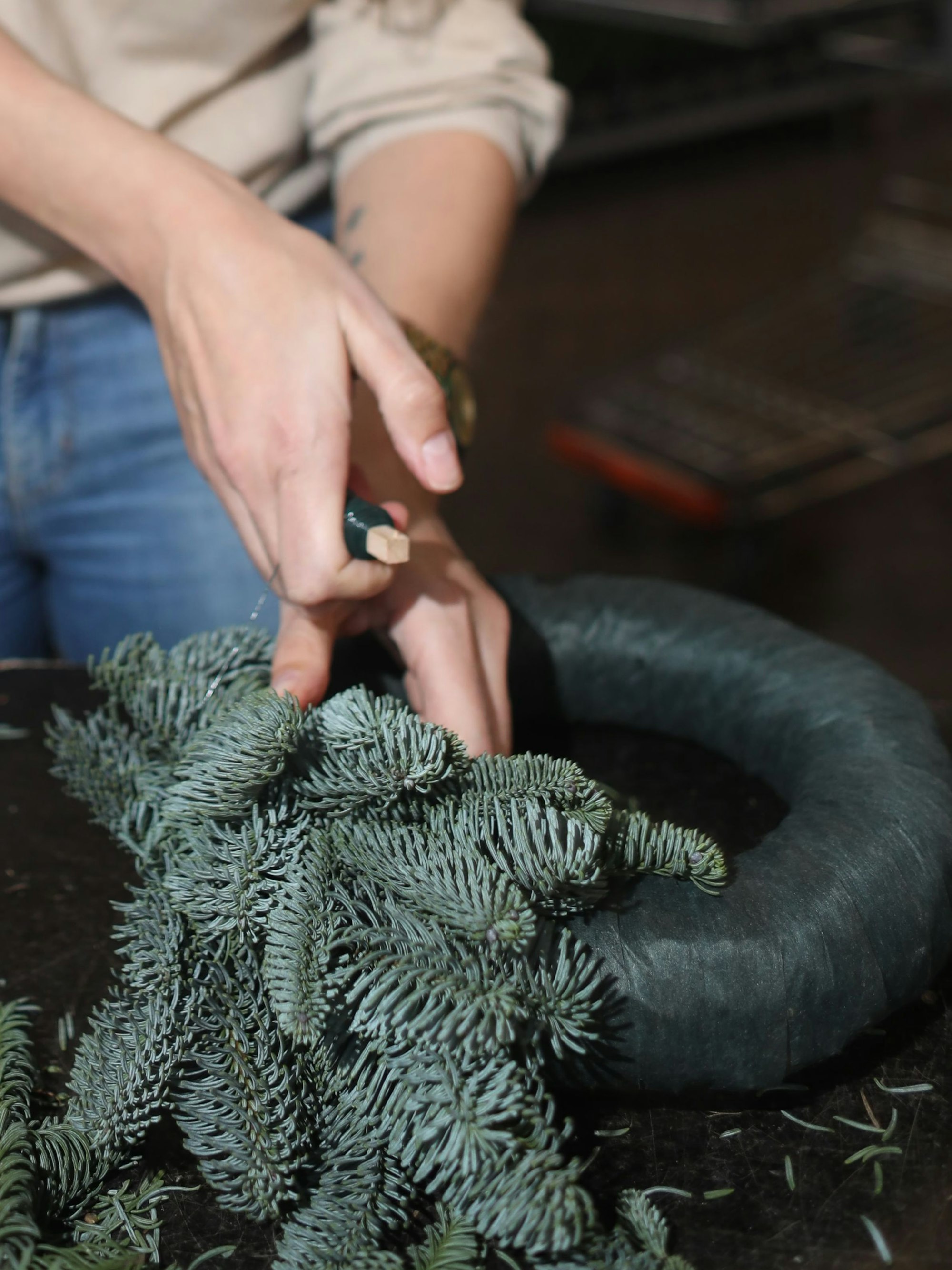 Den Rohling halten, Tannengrün andrücken, das Ganze mit Draht fixieren – mit zwei Händen ist das ganz schön ambitioniert.