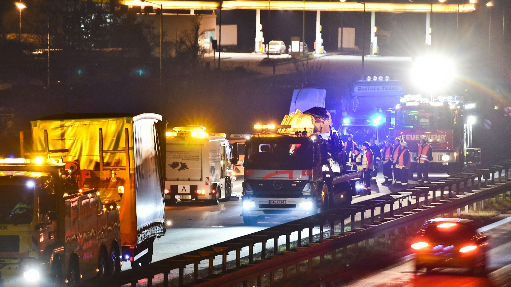 Rettungskräfte bei Bergungsarbeiten auf einer Autobahn, im Hintergrund eine Raststätte (Symbolfoto).