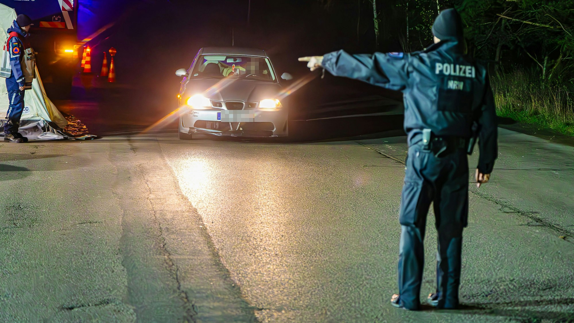 Das Bild zeigt einen Polizisten, der per Handzeichen eine Anweisung an einen Autofahrer gibt.