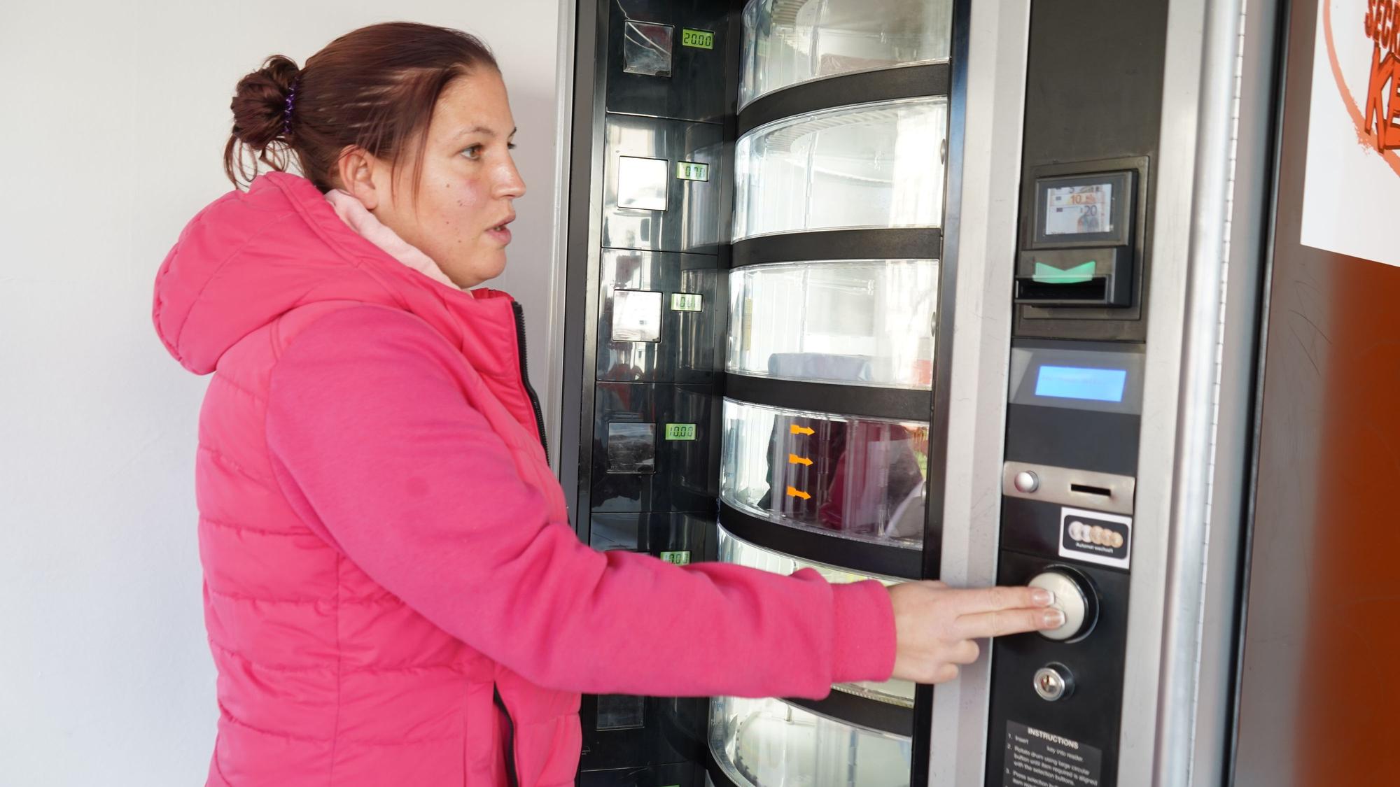 Das Foto zeigt eine Frau an einem Secret-Packs-Automaten.