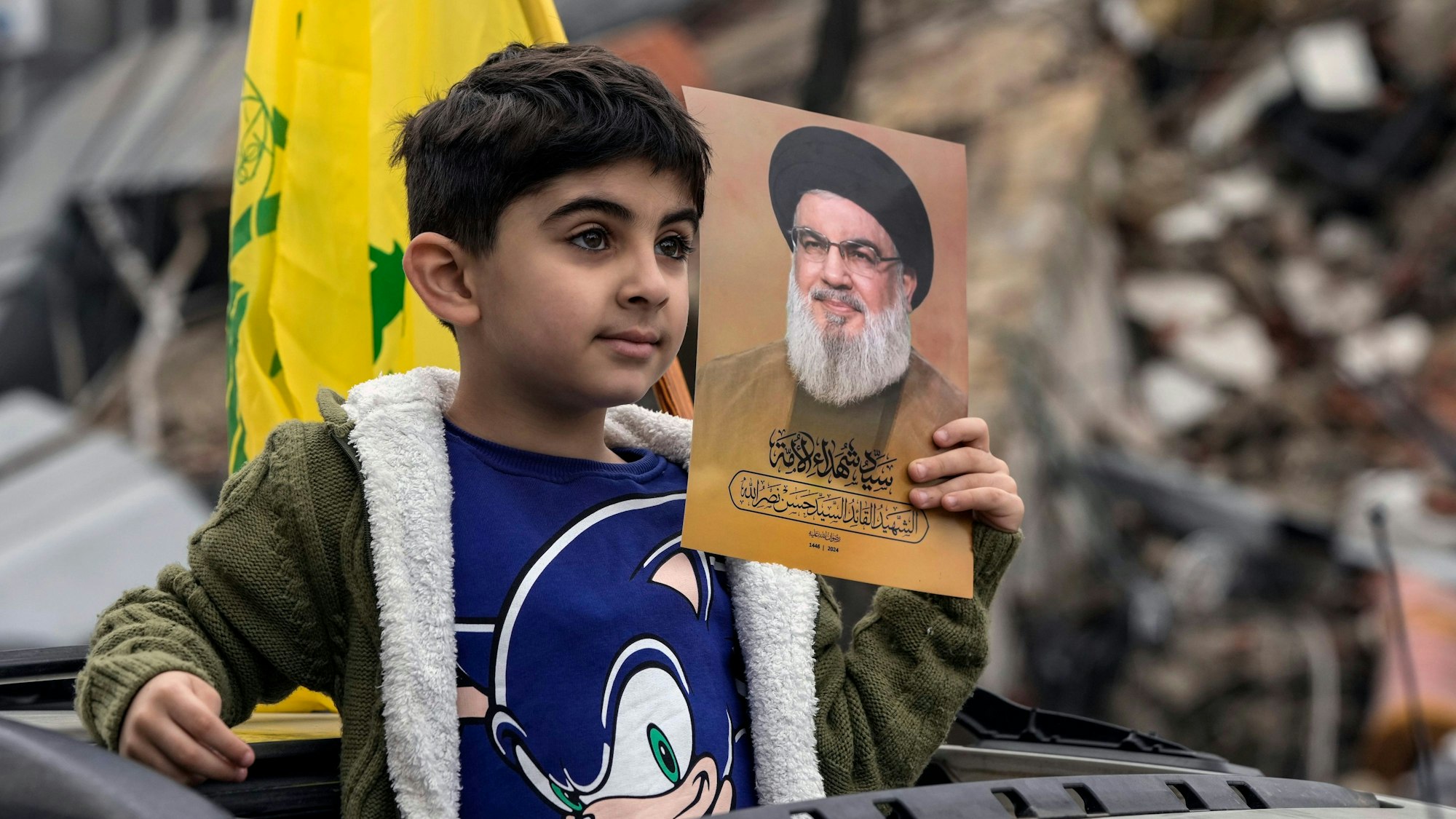 Ein vertriebener Junge, der ein Bild des getöteten Hisbollah-Führers Hassan Nasrallah hält, kehrt mit seiner Familie zurück, nachdem eine Waffenruhie zwischen Israel und der Hisbollah in Kraft getreten ist.