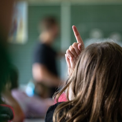 Ein Kind zeigt in einer Klasse auf.