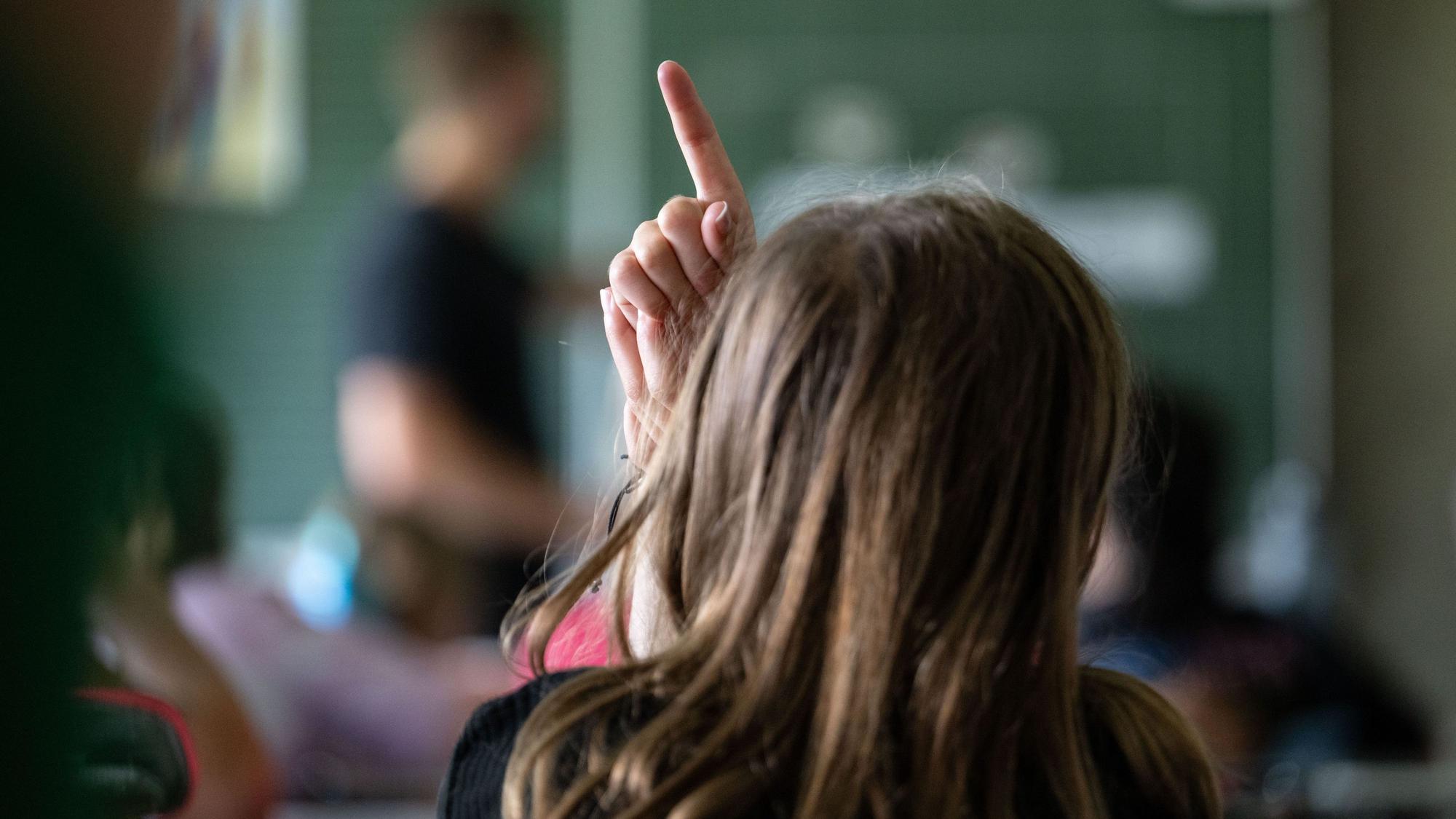 Ein Kind zeigt in einer Klasse auf.