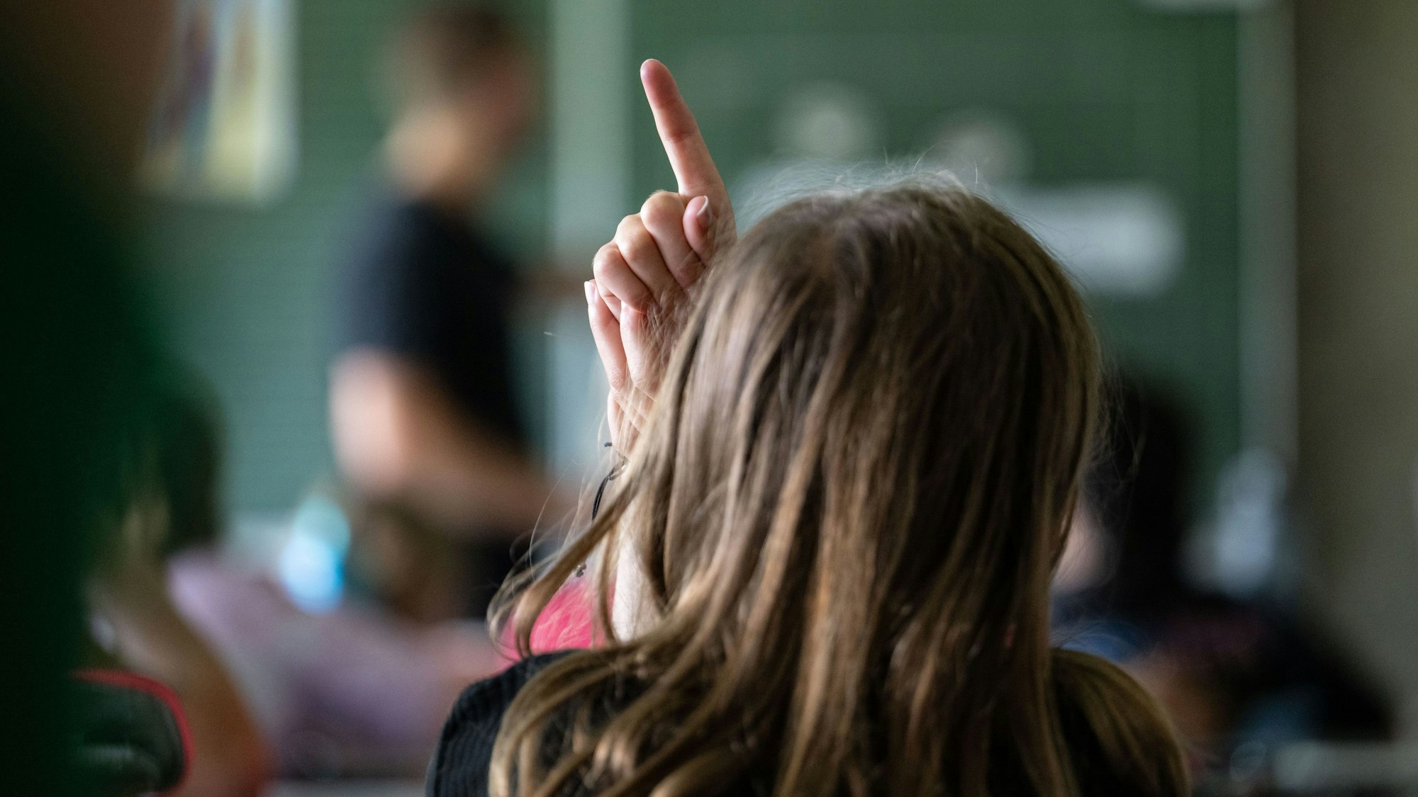 Ein Kind zeigt in einer Klasse auf.