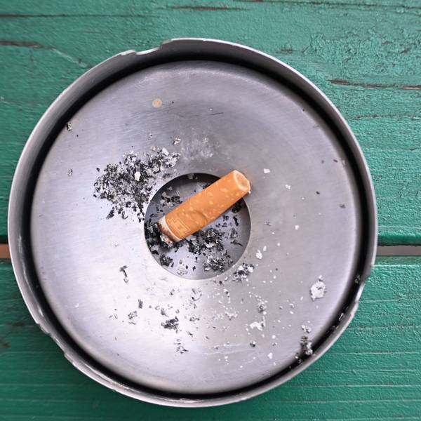 Im Freien liegt eine abgebrannte Zigarette in einem Aschenbecher.