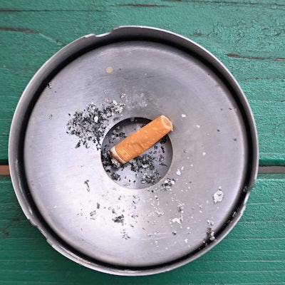 Im Freien liegt eine abgebrannte Zigarette in einem Aschenbecher.