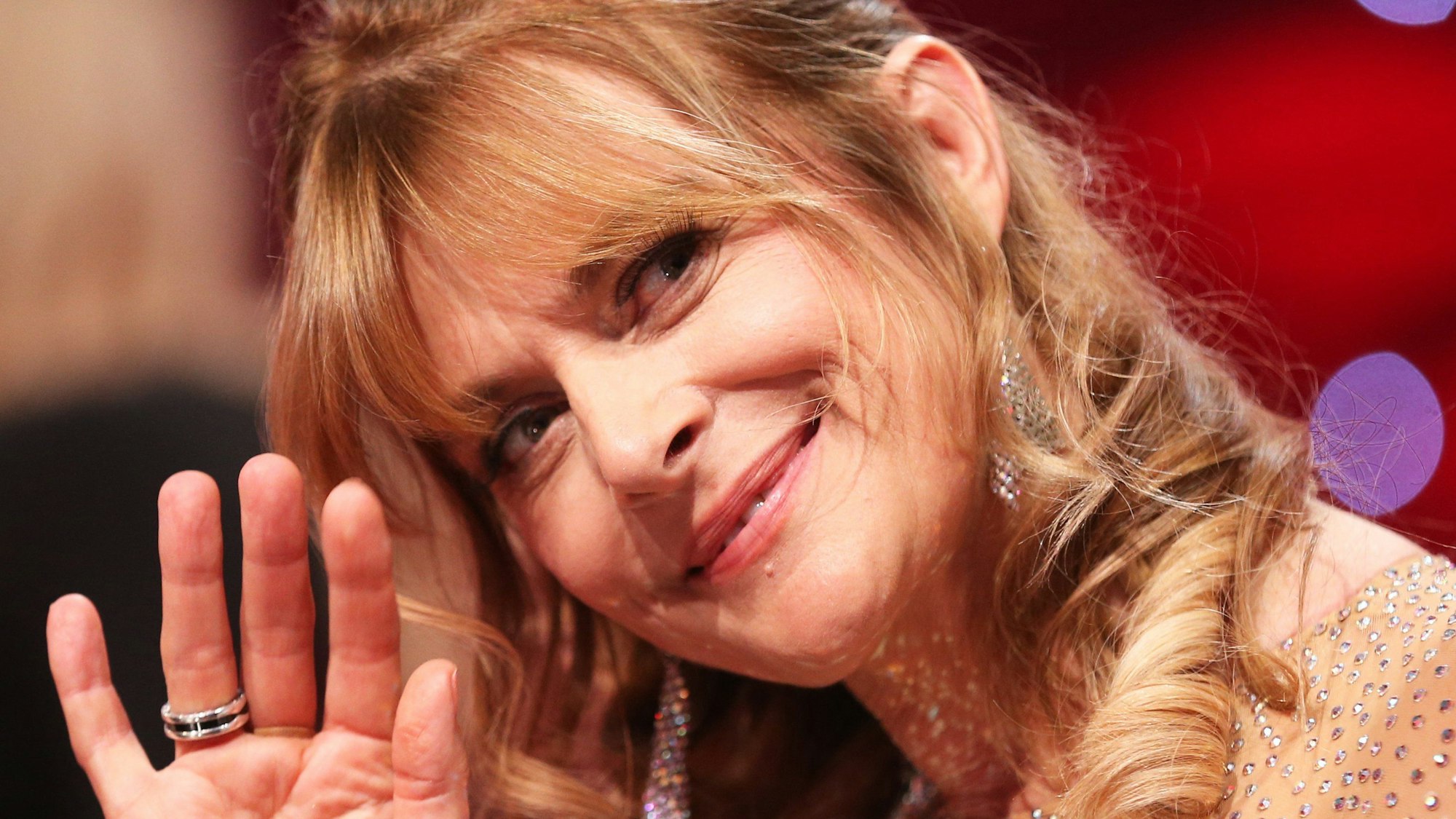 Nastassja Kinski winkt in die Kamera.