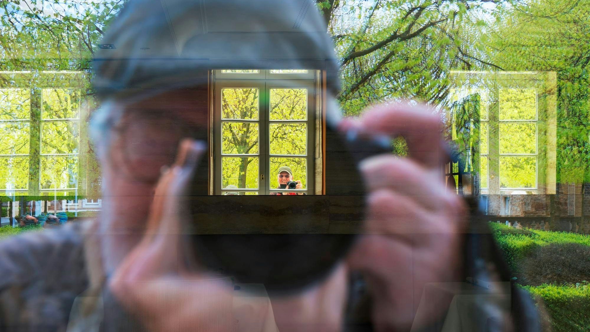 Ein Fotograf fotografiert seine eigene Spiegelung im Fenster.