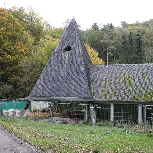 Eine Kapelle mit Turm und Trauerhalle, auf das Schieferdach wächst zum Teil Moos.