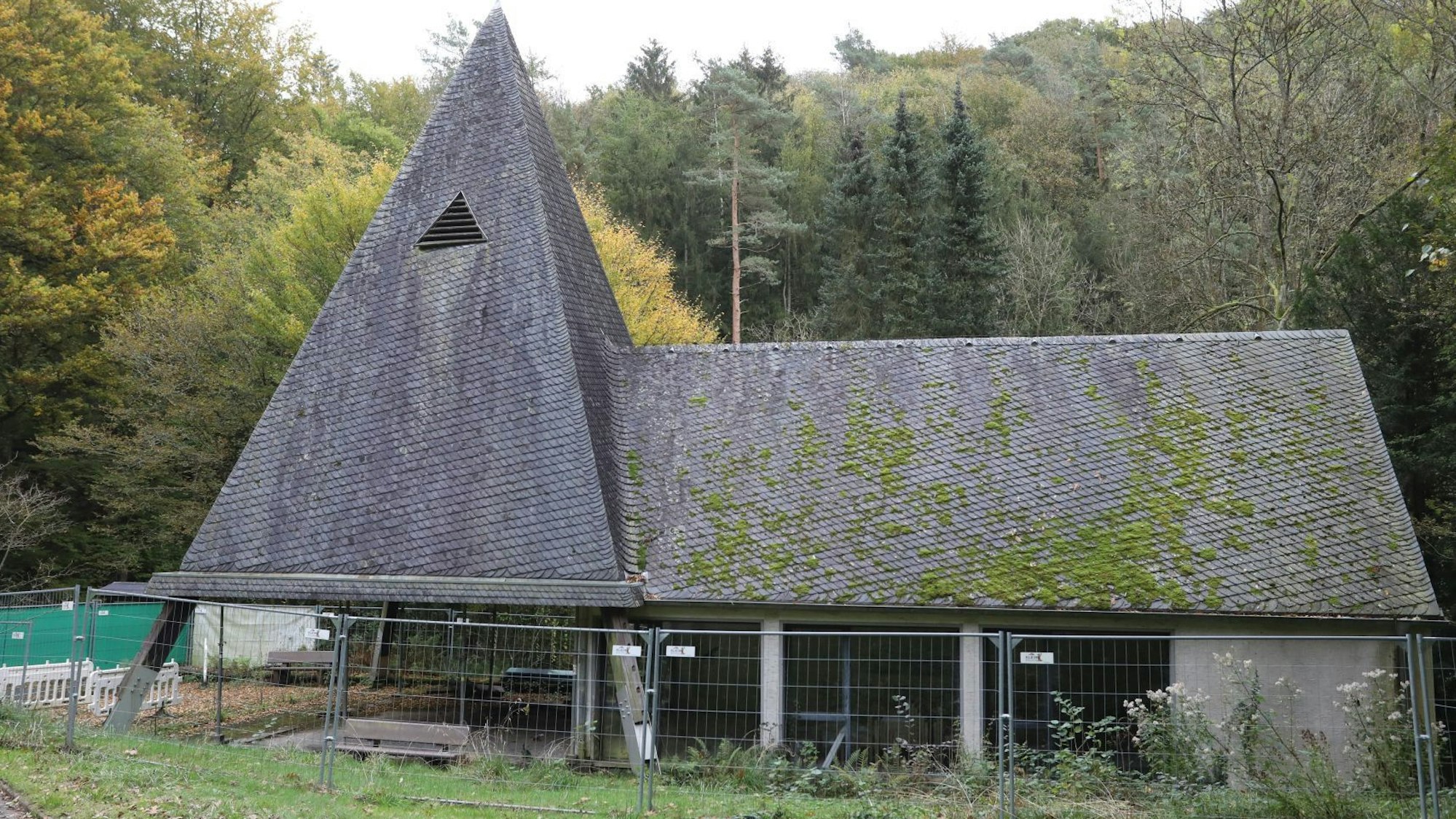 Eine Kapelle mit Turm und Trauerhalle, auf das Schieferdach wächst zum Teil Moos.