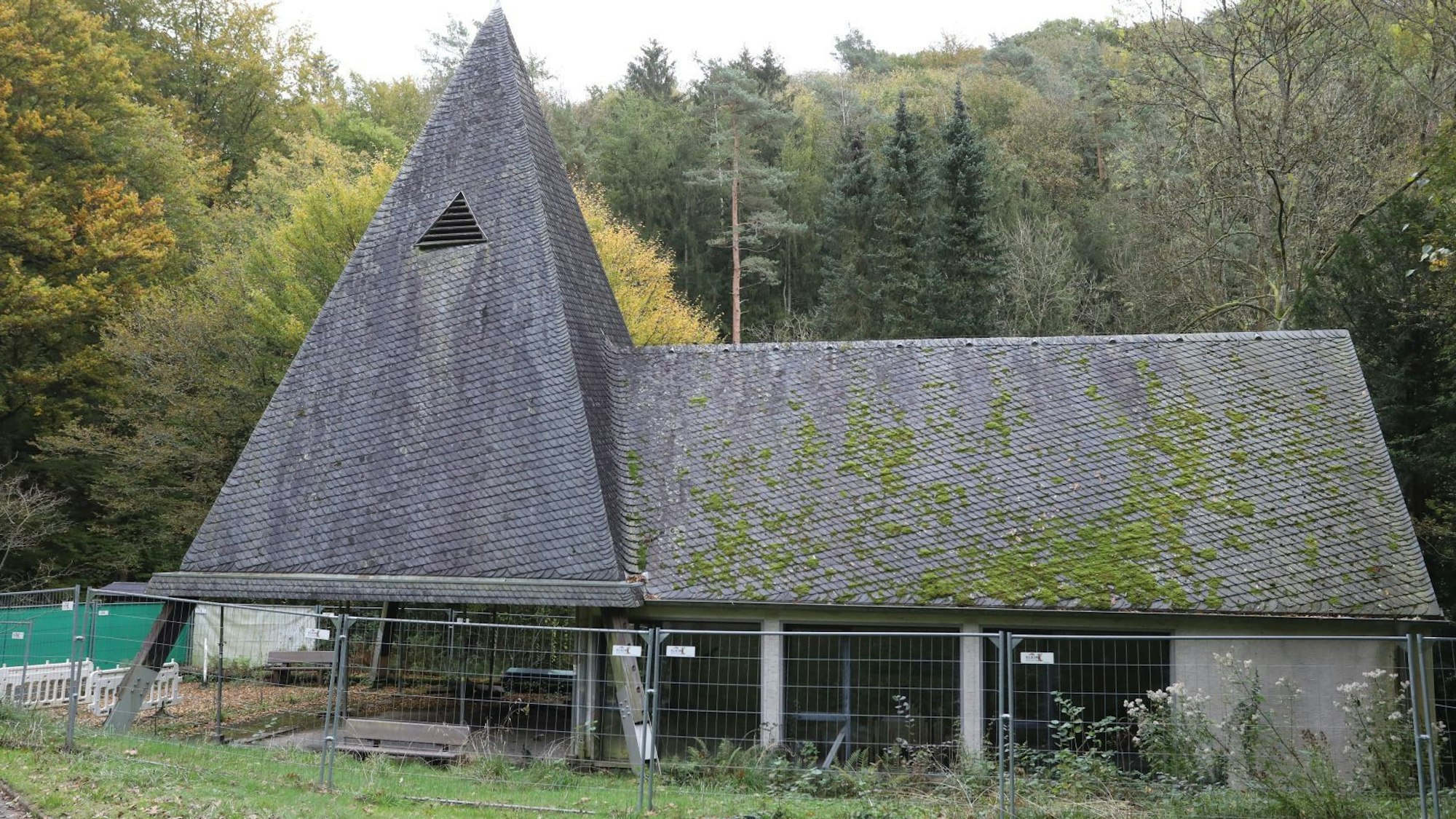 Eine Kapelle mit Turm und Trauerhalle, auf das Schieferdach wächst zum Teil Moos.