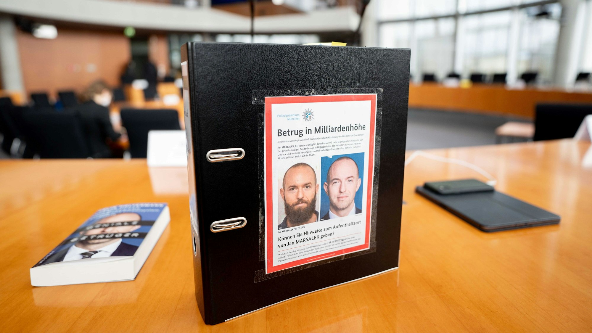 ARCHIV - 15.04.2021, Berlin: Der Aktenordner des ehemaligen Bundestagsabgeordneten de Masi (Die Linke) mit Fahndungsfotos des früheren Wirecard-Finanzvorstands Jan Marsalek ist im Sitzungssaal zum Bilanzskandal Wirecard im Paul-Löbe-Haus zu sehen.