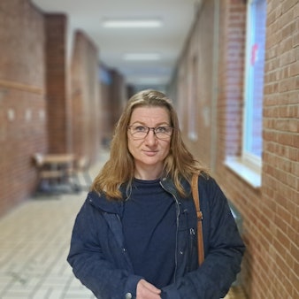 Eine Frau steht in einem Flur eines Schulgebäudes