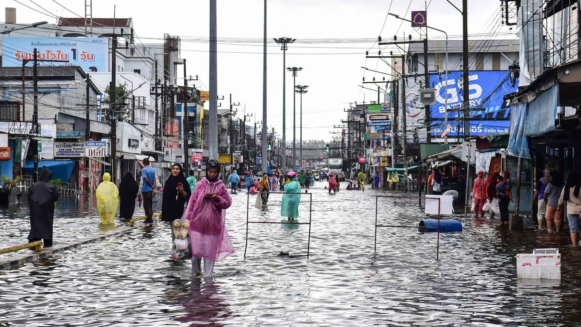 People wade through flood waters following heavy rain in Thailand's southern province of Narathiwat on November 27, 2024.