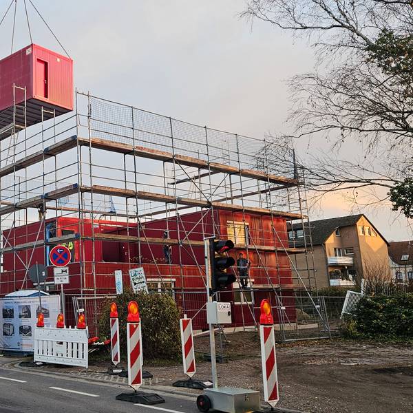 Ein Mobilkran hievt Container aufeinander, eine Unterkunft für Geflüchtete entsteht.