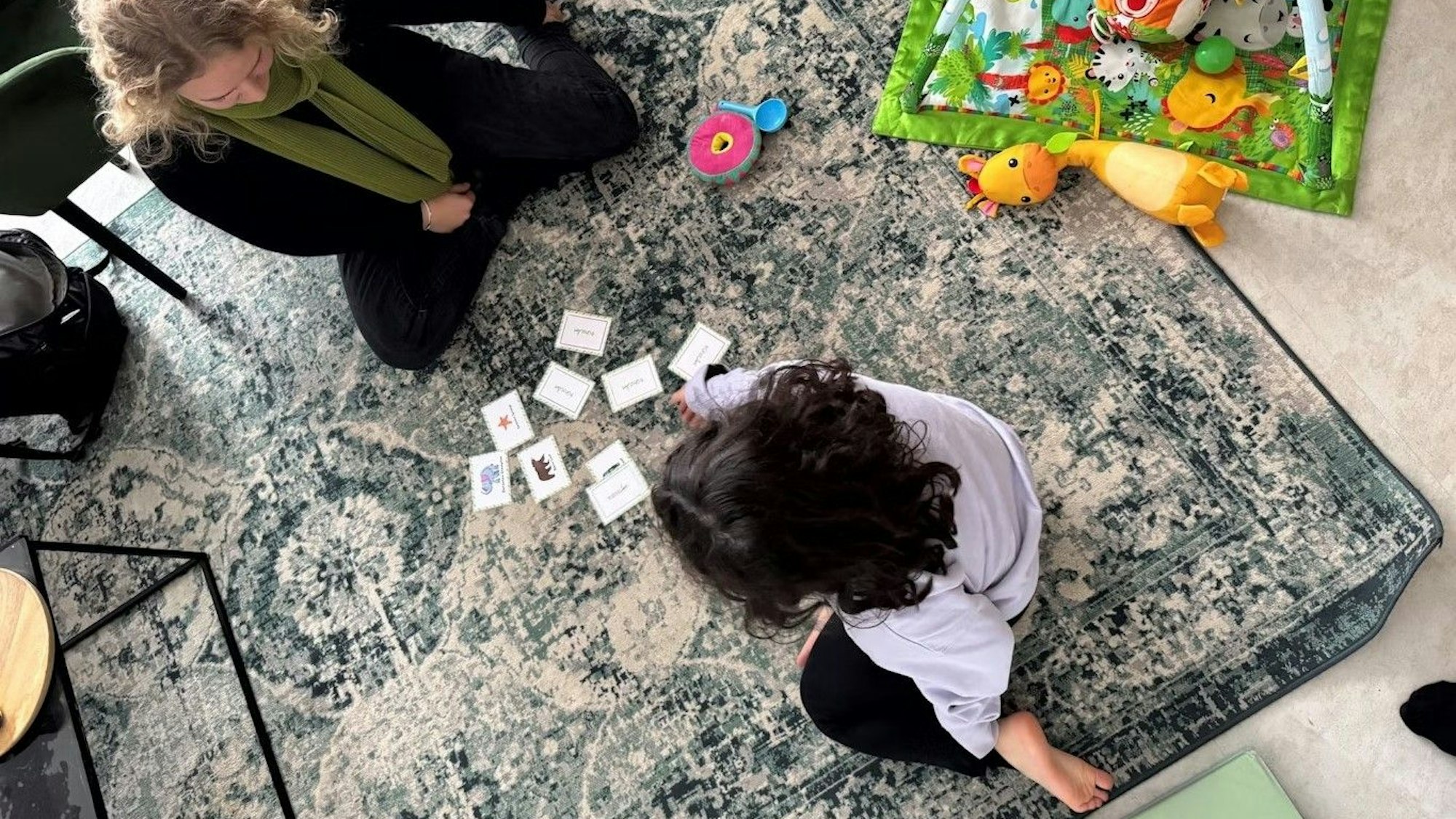 Lena Duske von Frühstart sitzt mit einem dunkelhaarigen Mädchen auf dem Boden und spielt.