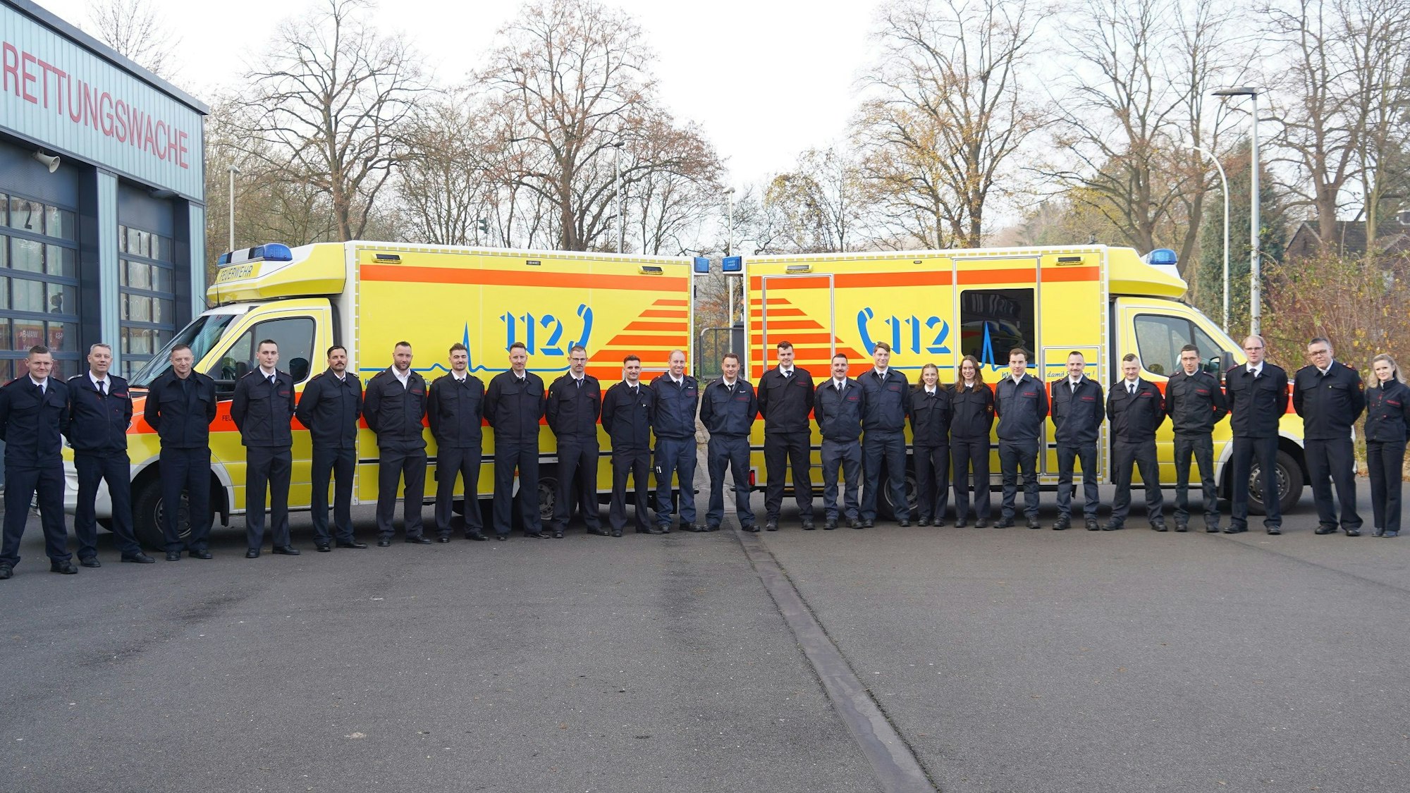 Auf dem Bild sind zwei Krankenwagen und eine Gruppe von Menschen in Uniform zu sehen.