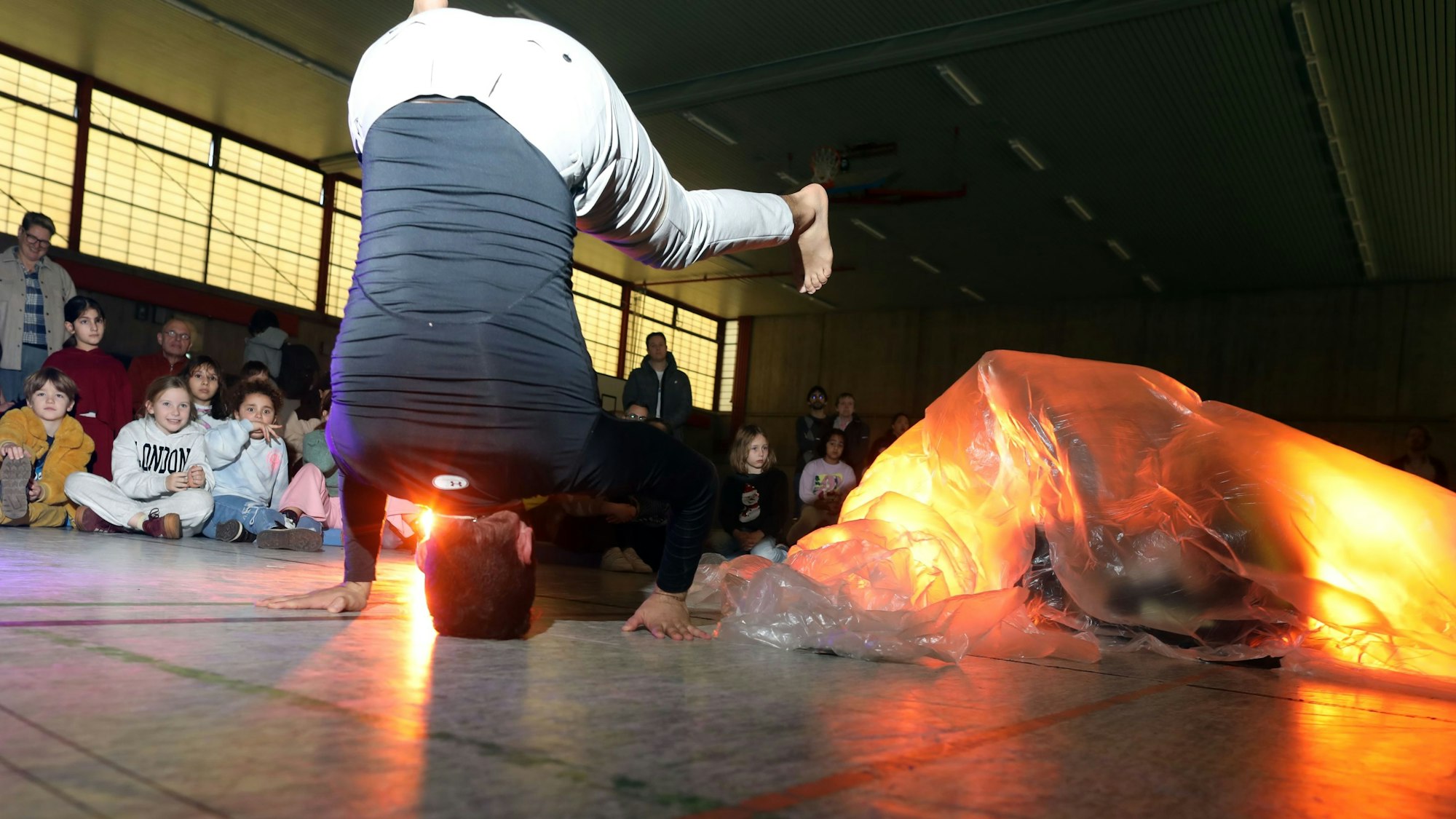 Ein Tänzer der Offenen Jazz Haus Schule tanzt auf dem Kopf in eíner Turnhalle