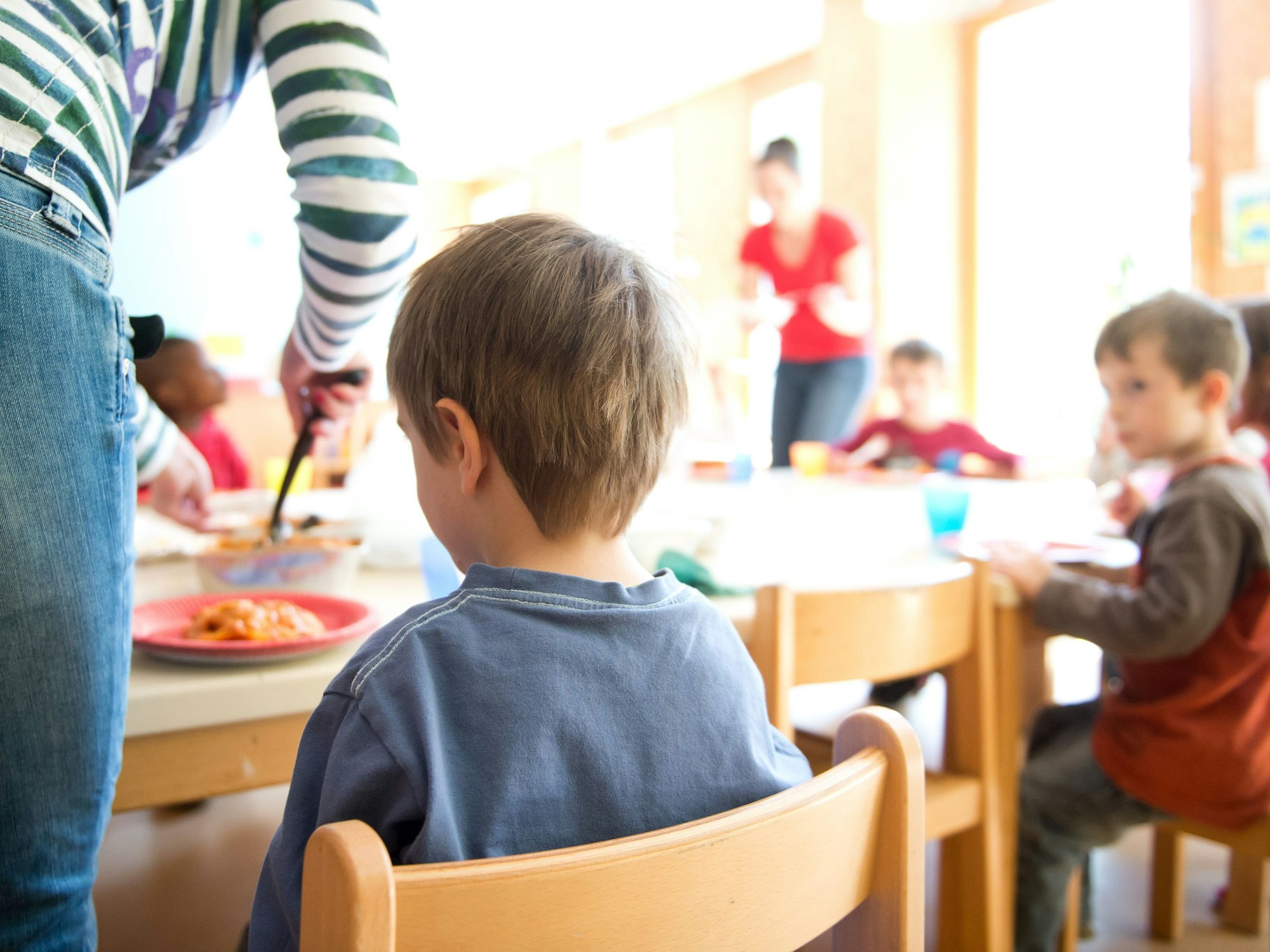 Eine Mutter serviert Kindern Lasagne zum Mittagessen in Stuttgart in einer Kindertagesstätte.
