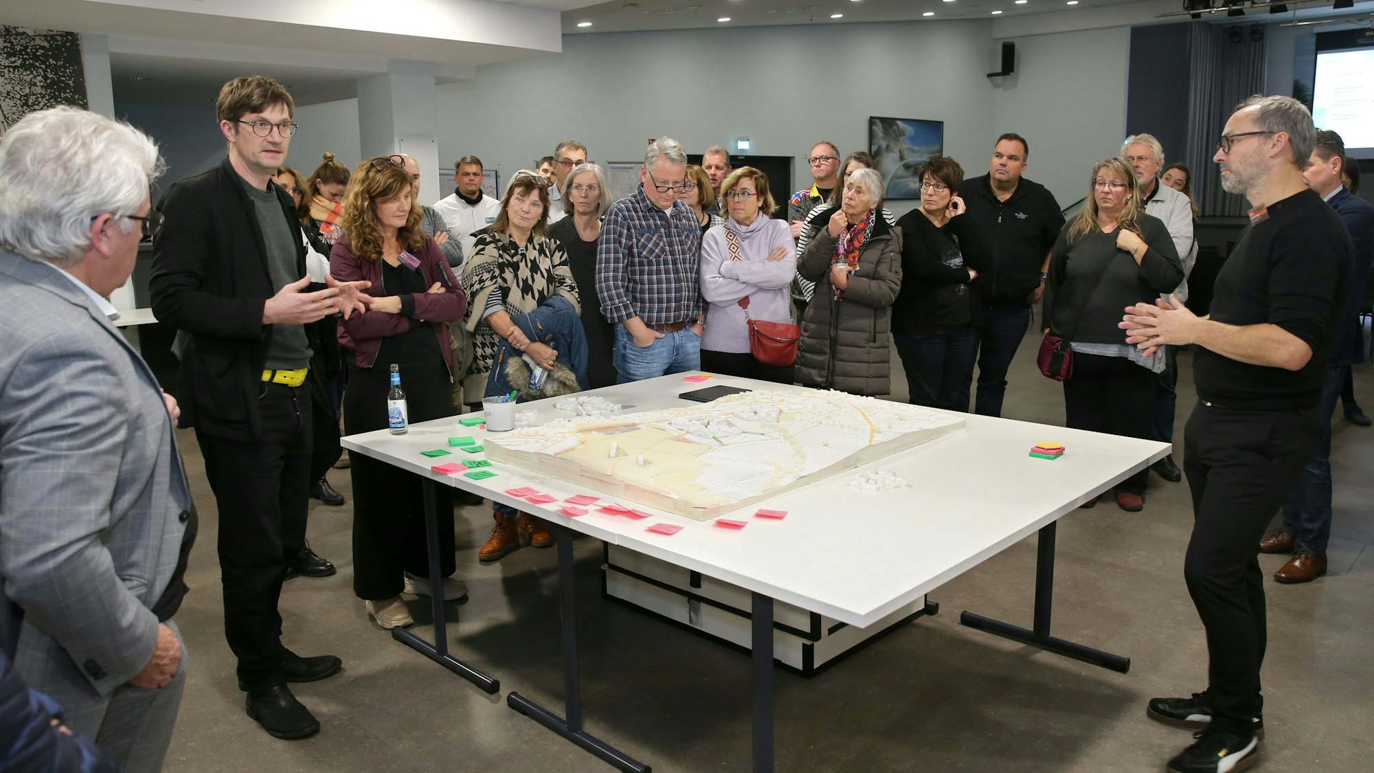 Eine Gruppe steht rund um einen Kartentisch.