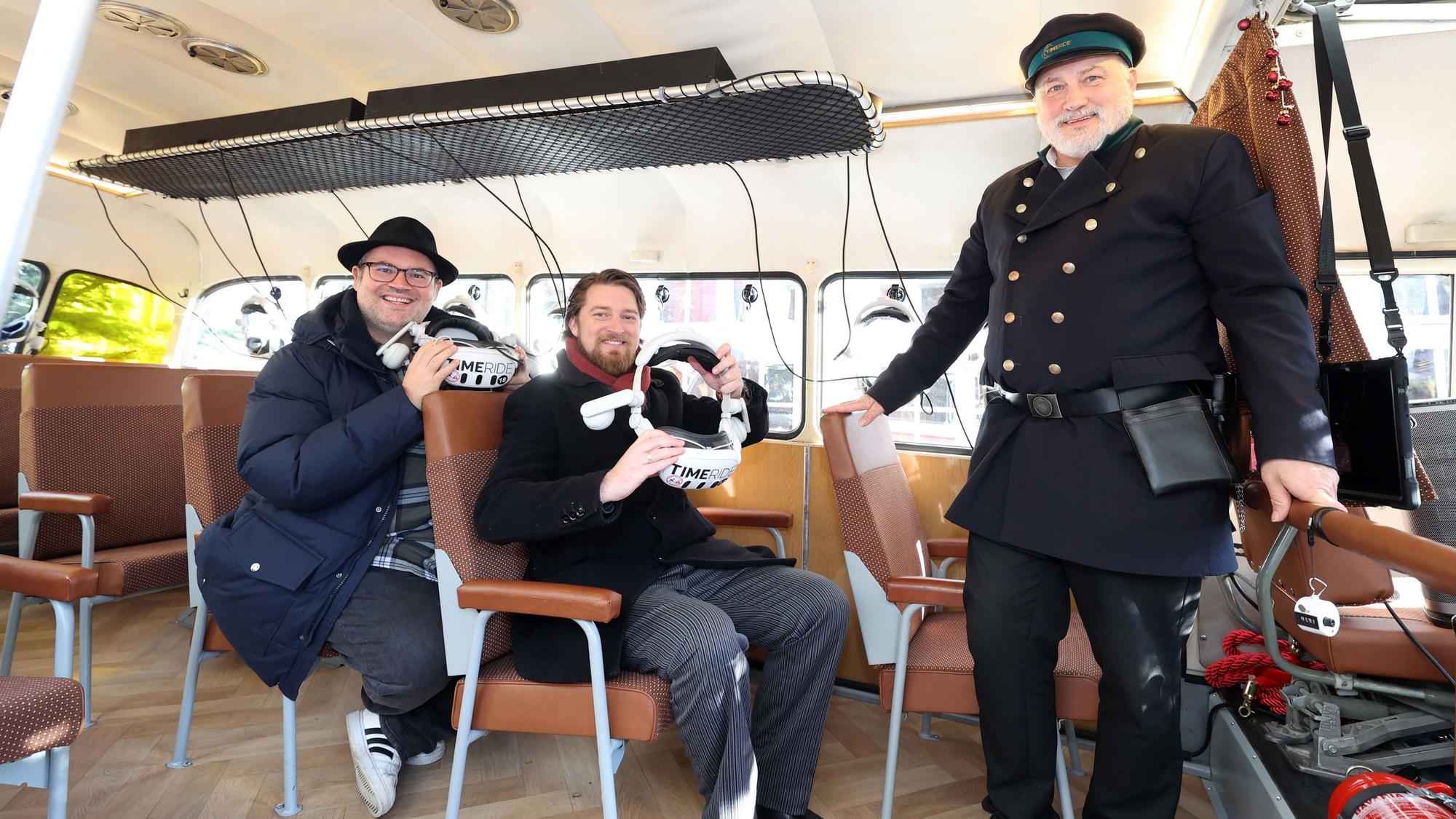 Björn Heuser, Jonas Rothe und Helge Maus sind im Oldtimer-Bus und halten VR-Brillen in der Hand.