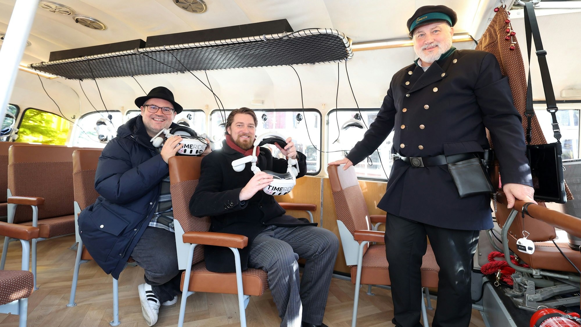 Björn Heuser, Jonas Rothe und Helge Maus sind im Oldtimer-Bus und halten VR-Brillen in der Hand.