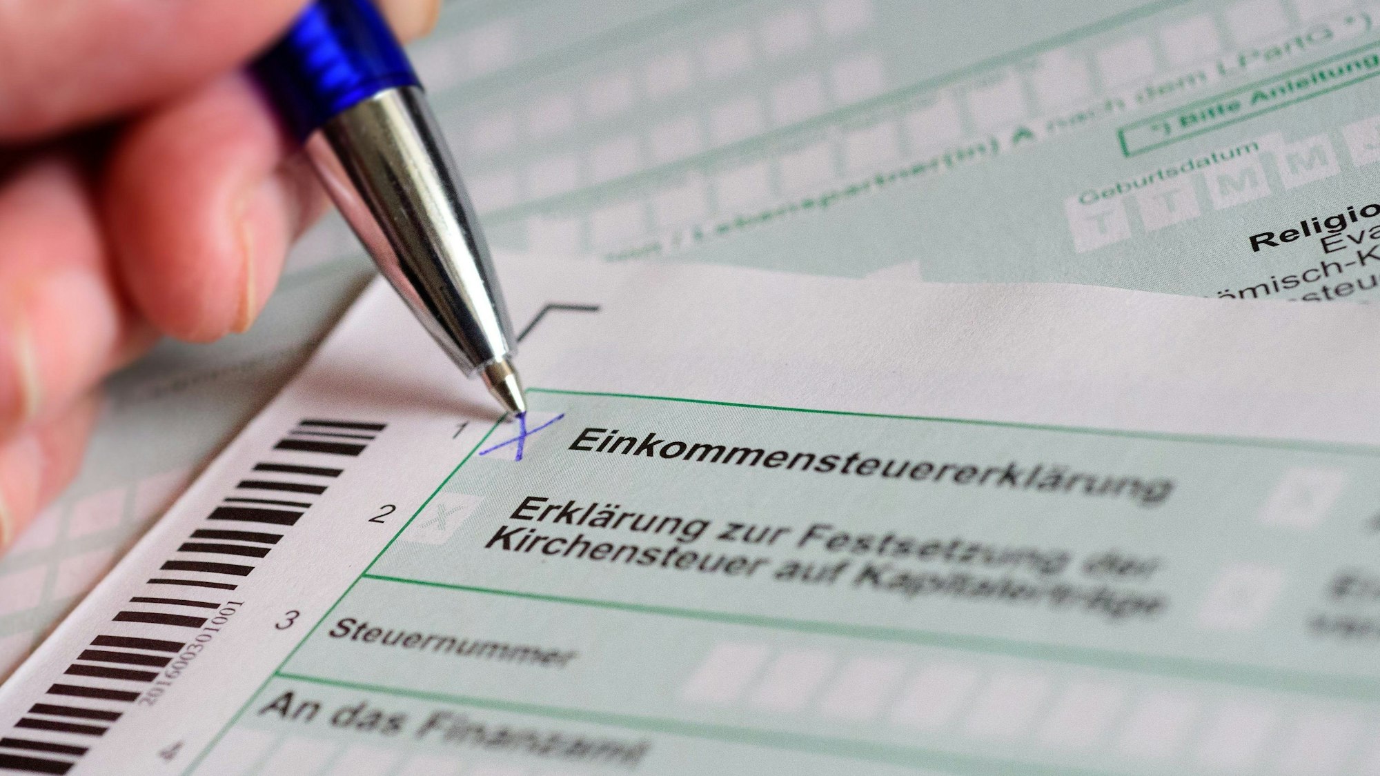 ARCHIV - 10.04.2017, Berlin: Eine Hand mit Kugelschreiber setzt ein Kreuz bei «Einkommensteuererklärung» auf dem offiziellen Formular des Finanzamts.