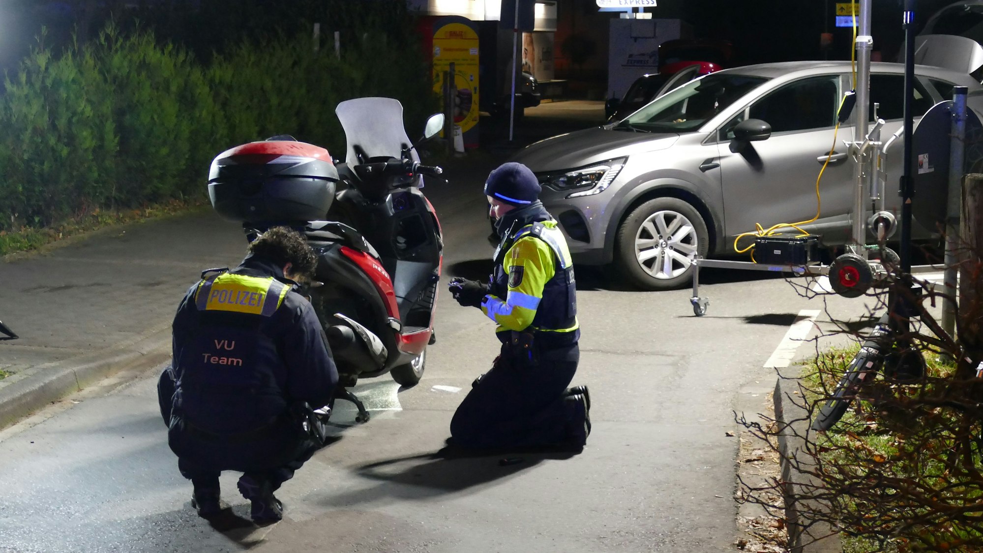 Polizeibeamte untersuchen den Motorroller.