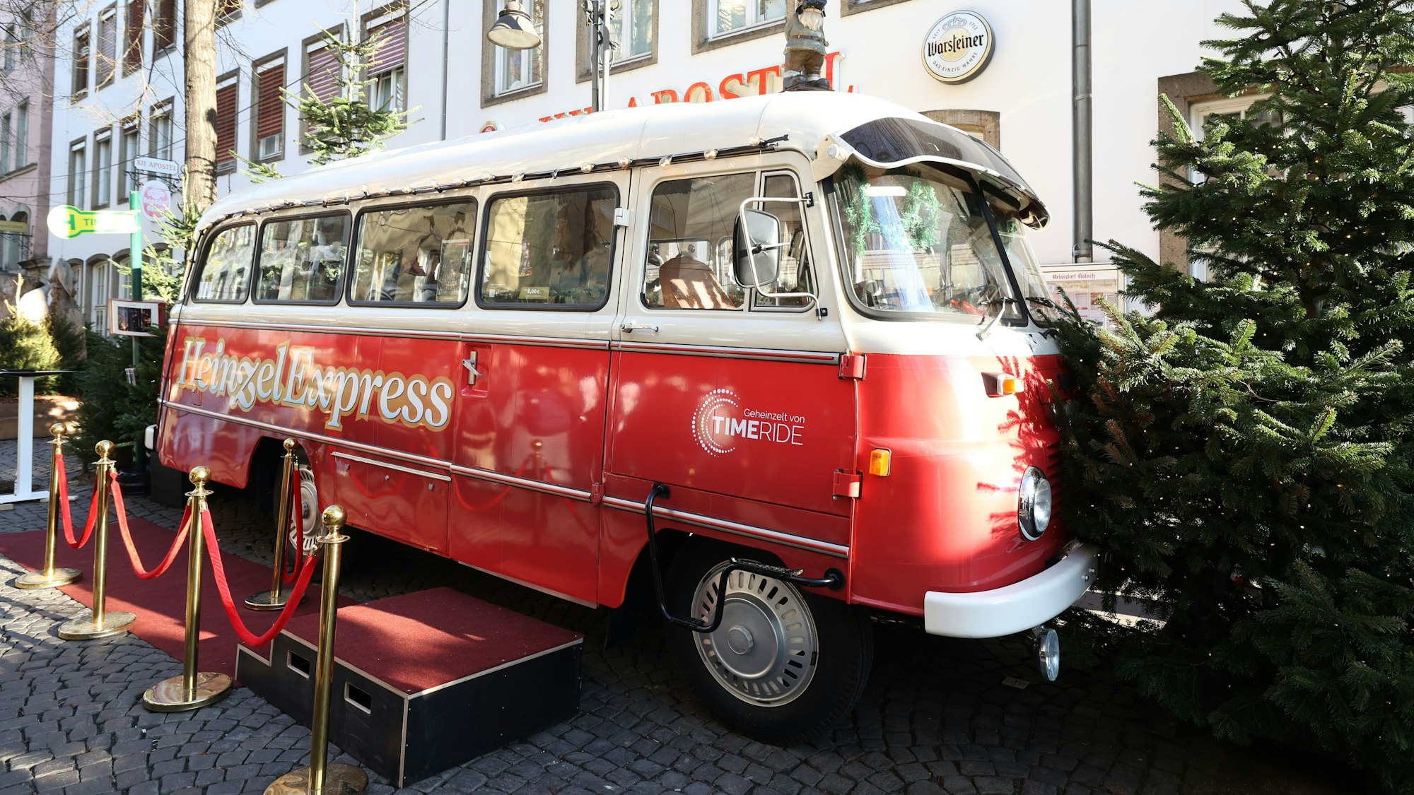 Ein roter Oldtimer-Bus steht neben einem Weihnachtsbaum.